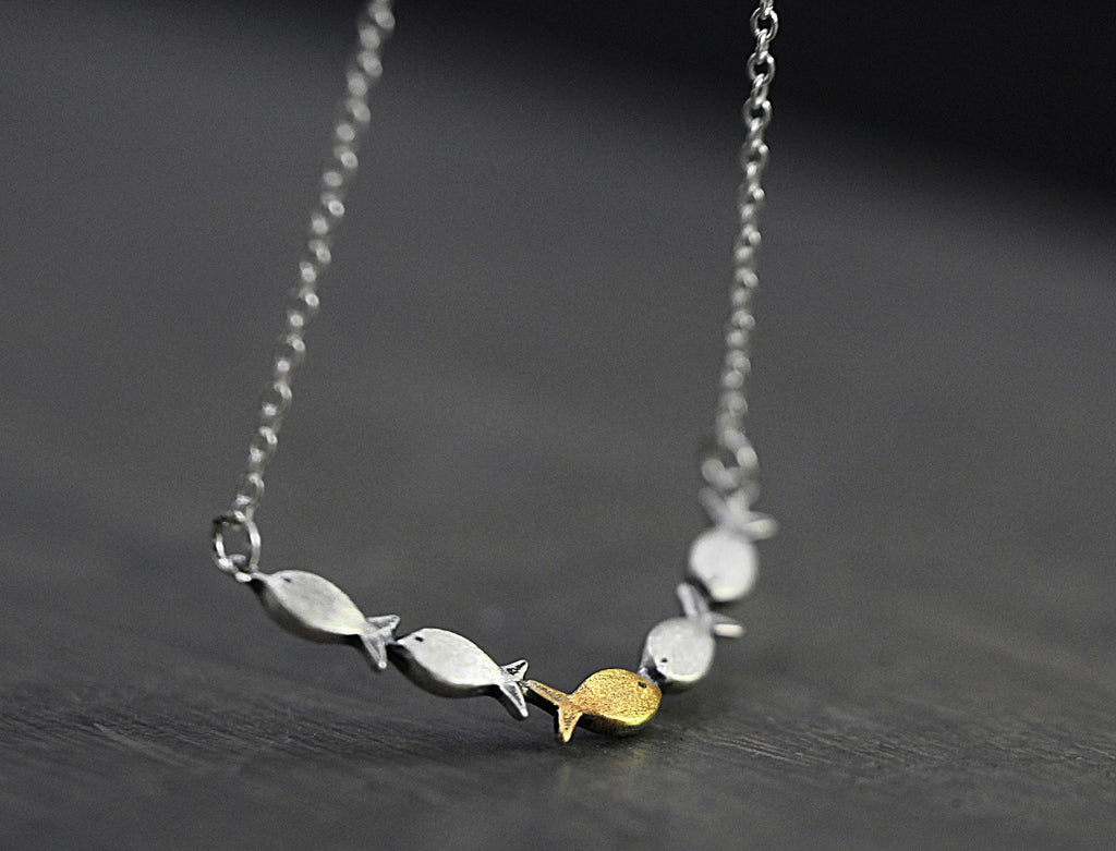 Swimming against the current. Dainty silver necklace. School of fish with one golden enameled fish swimming upstream. Gift for her.