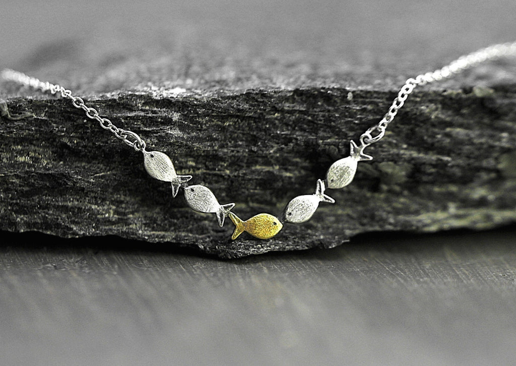 Swimming against the current. Dainty silver necklace. School of fish with one golden enameled fish swimming upstream. Gift for her.