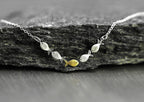 Swimming against the current. Dainty silver necklace. School of fish with one golden enameled fish swimming upstream. Gift for her.