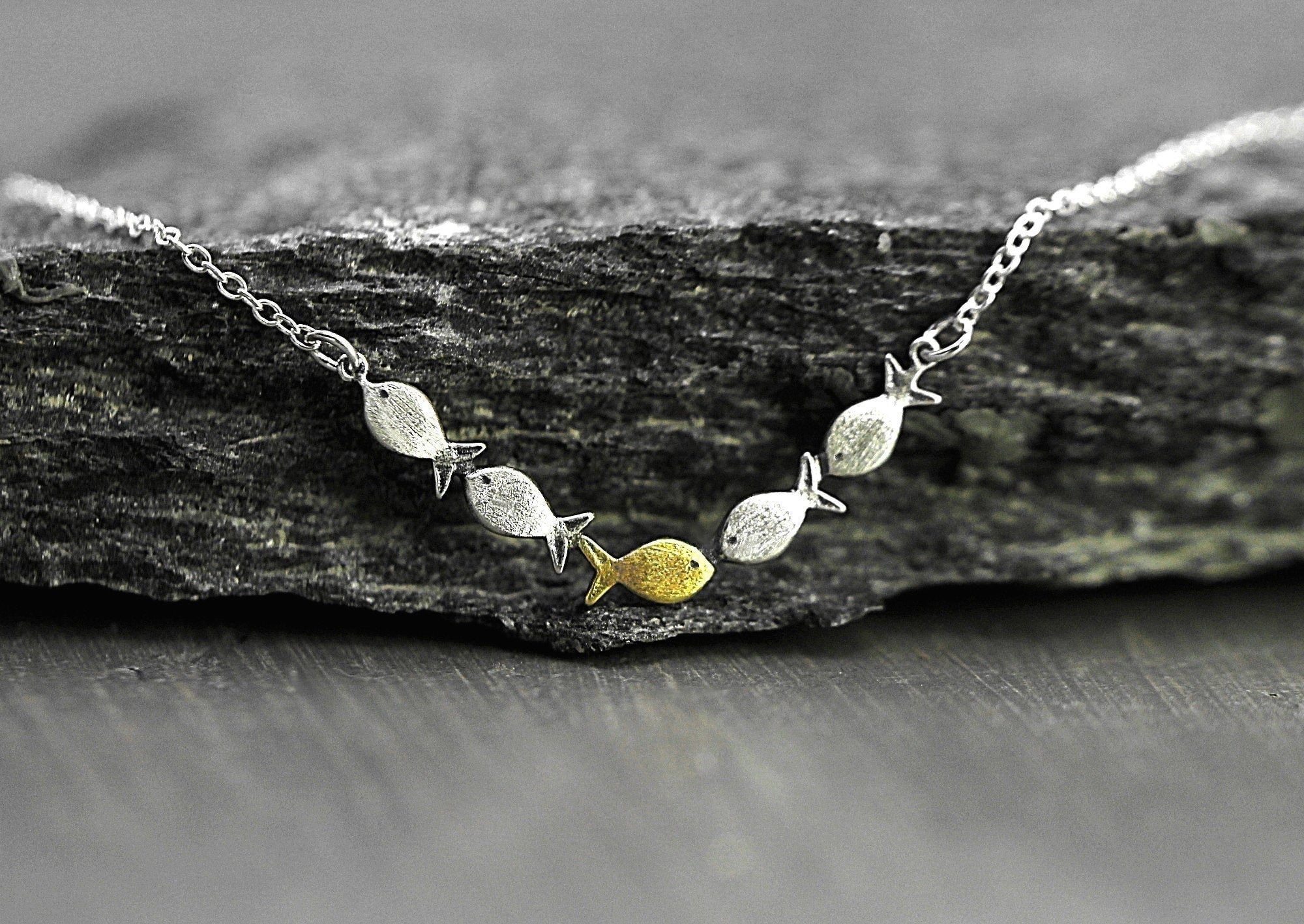 Swimming against the current. Dainty silver necklace. School of fish with one golden enameled fish swimming upstream. Gift for her.