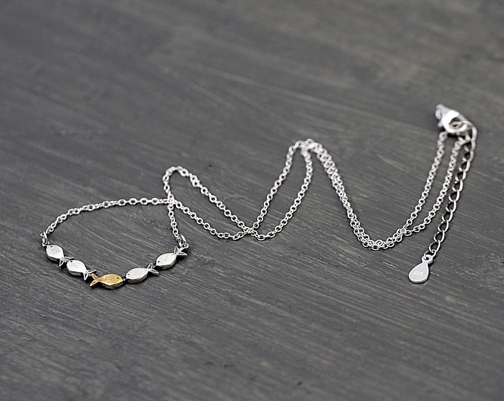 Swimming against the current. Dainty silver necklace. School of fish with one golden enameled fish swimming upstream. Gift for her.
