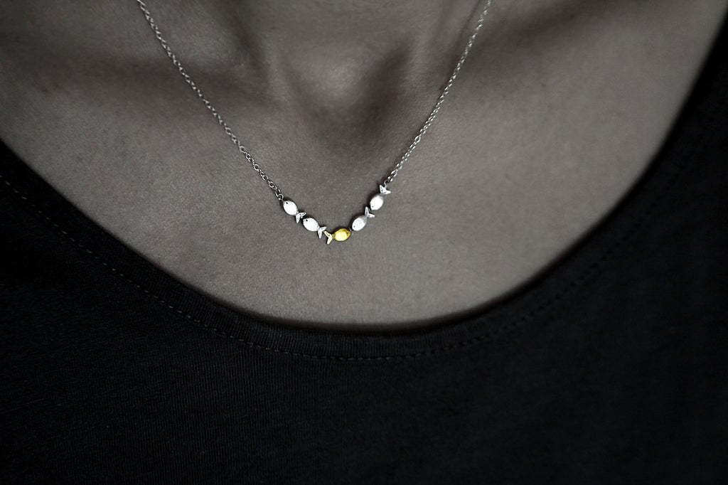 Swimming against the current. Dainty silver necklace. School of fish with one golden enameled fish swimming upstream. Gift for her.