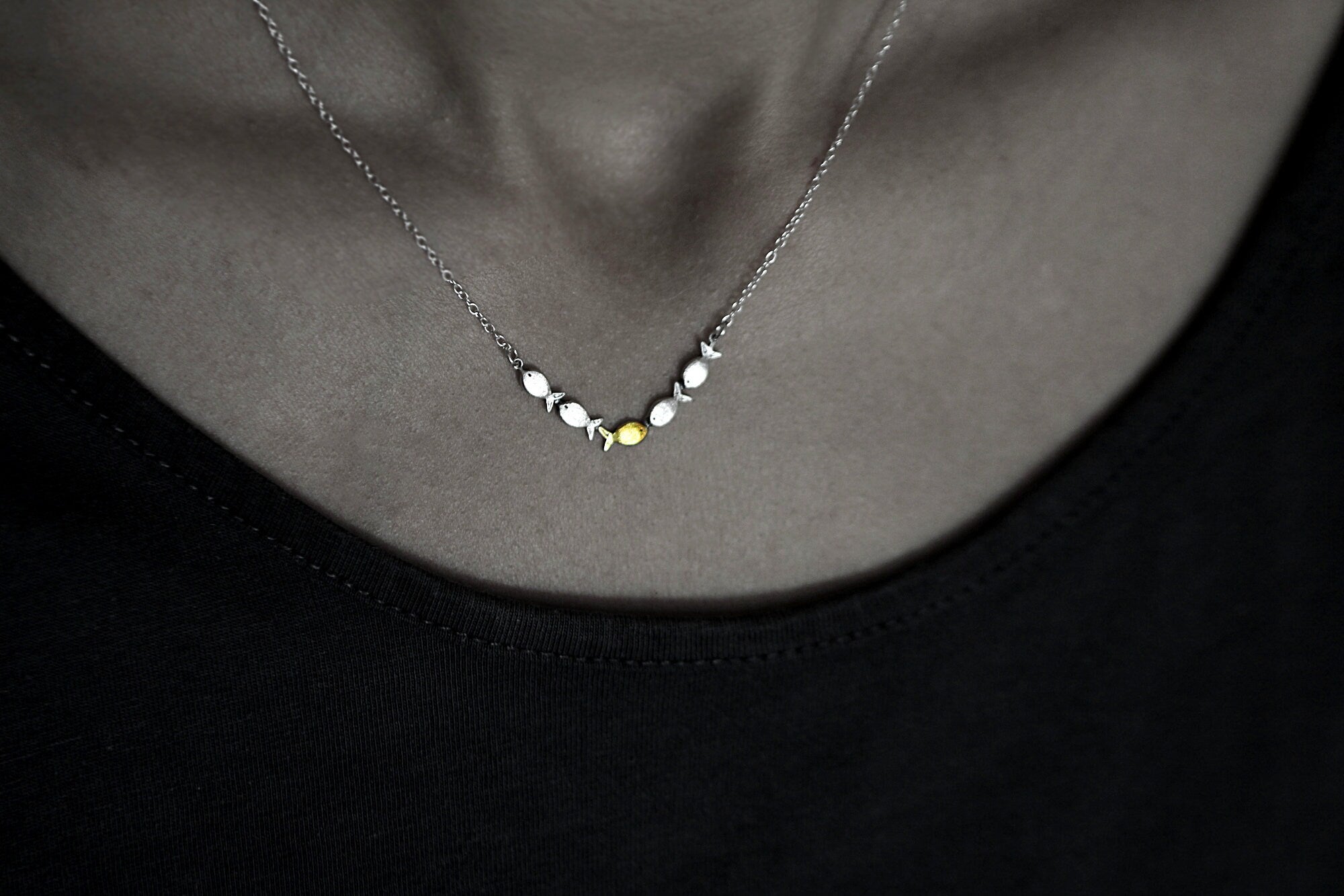 Swimming against the current. Dainty silver necklace. School of fish with one golden enameled fish swimming upstream. Gift for her.